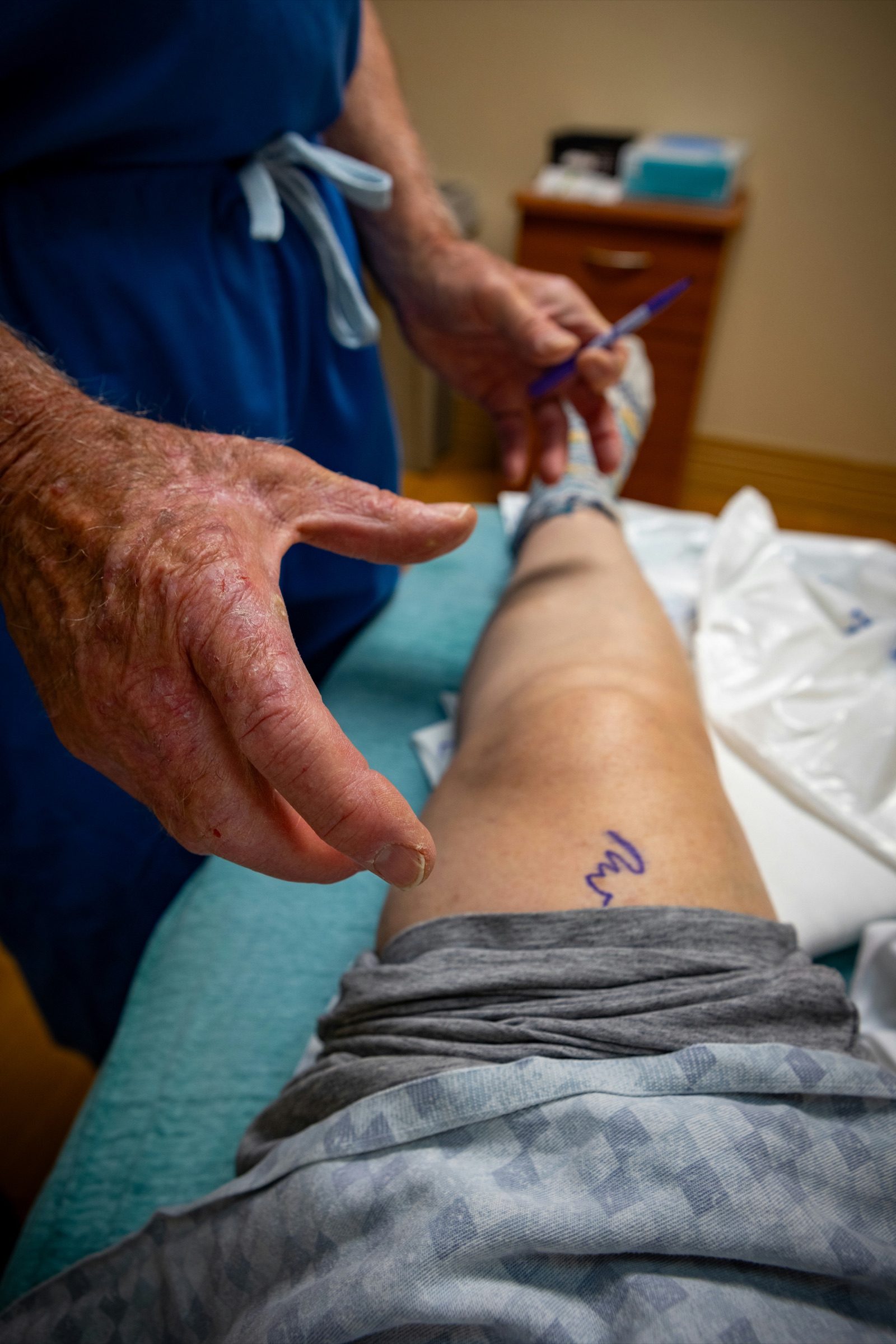 A clinician examining a patient’s knee before surgery